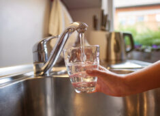 Close up of children hands, pouring glass of fresh water from tap in kitchen